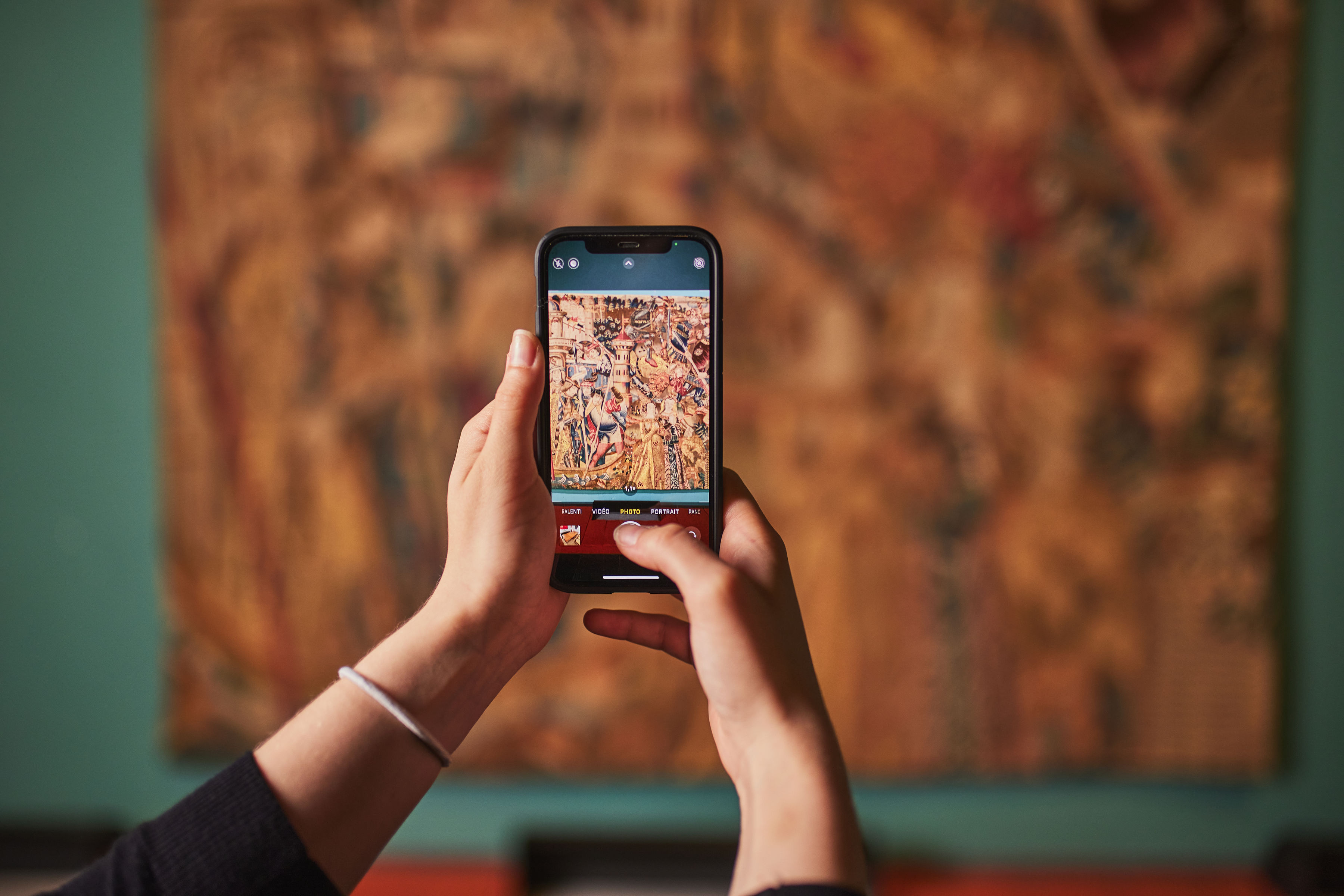 Personne prenant en photo avec un smartphone une tapisserie au musée de la Tapisserie et des Arts textiles 